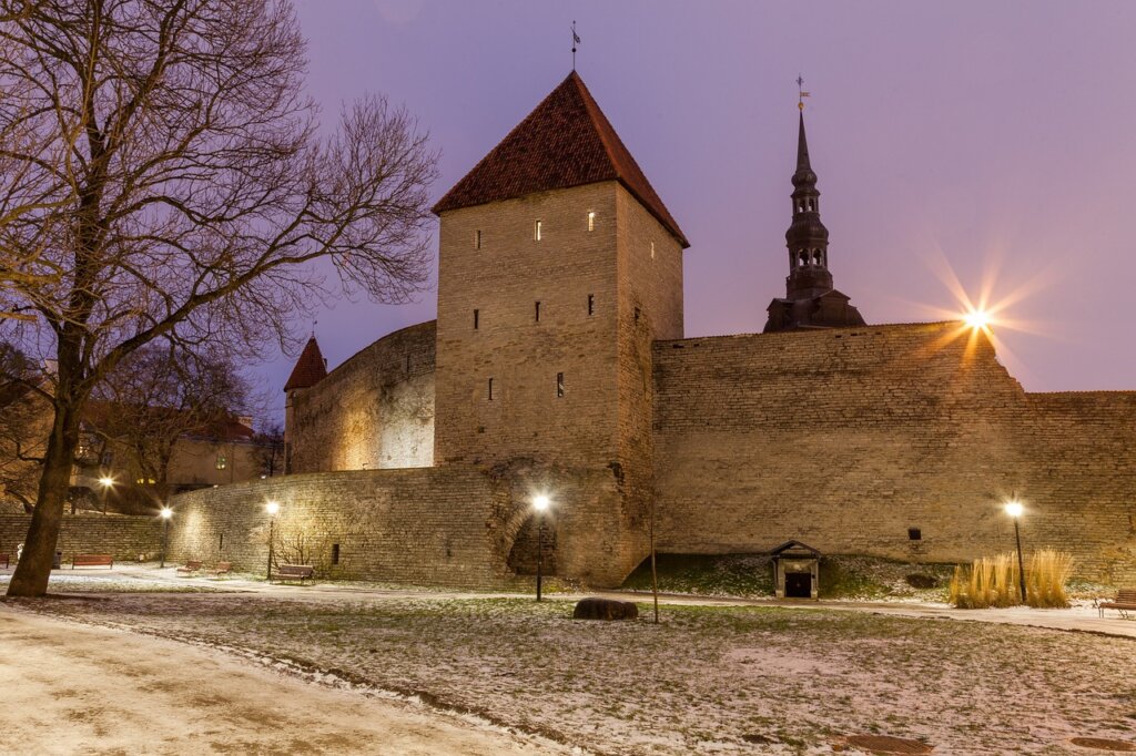 a stone wall with a tower and a snow covered ground